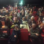 la salle pas tout à fait pleine encore, les retardataires arrivent